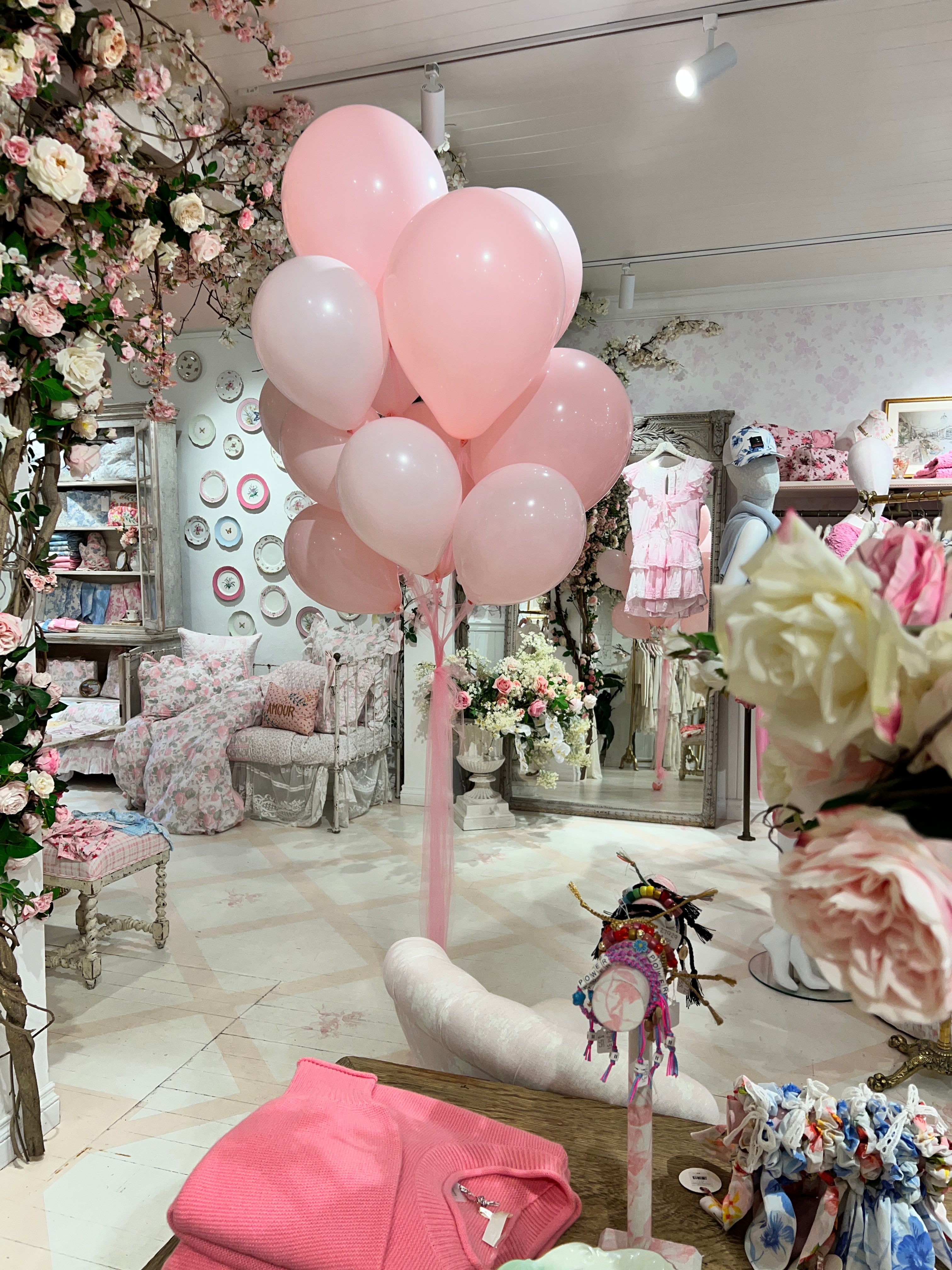 Decorative setup with pink balloons and flowers in love shack fancy with mirrors and clothing.