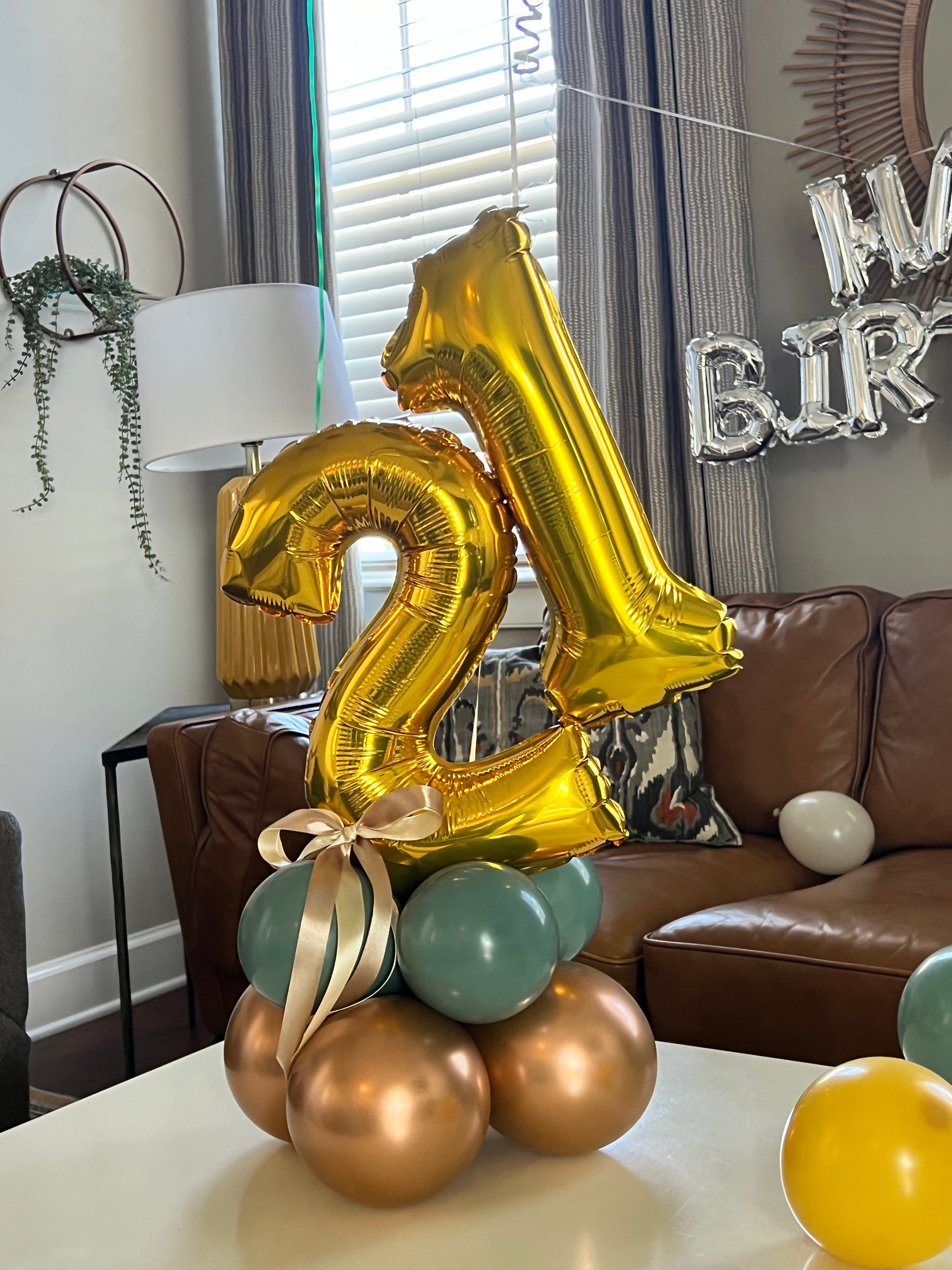 Gold number 21  balloon and other balloons on a table 