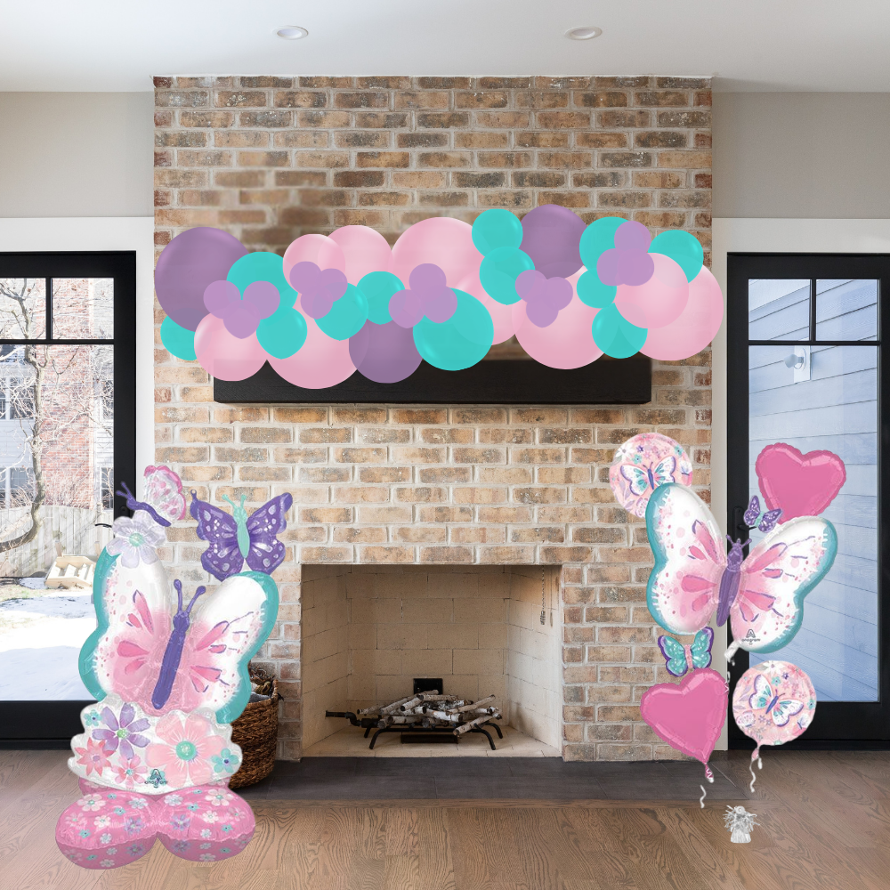 Decorative balloon arch with pink, purple, and teal balloons above a fireplace.