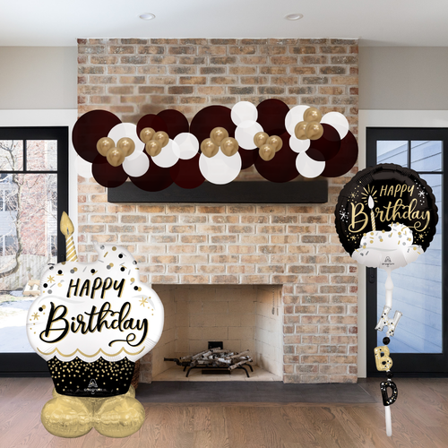 Birthday decorations including balloons and signs in front of a brick fireplace.